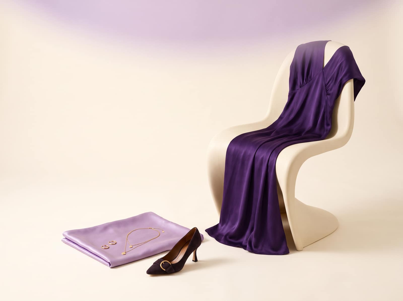 Bodegón editorial: vestido morado, seda lila, joyas y un tacón